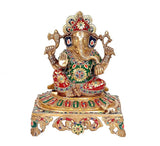 Ganesha deity brass idol statue seated on ornate pedestal with colorful decorations