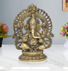 Brass Ganesha idol, seated with ornate halo and raised hands, highly detailed face