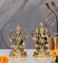 Brass Lakshmi and Ganesha idol pair, seated with raised hands on round bases.
