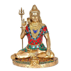 Brass Lord Shiva statue front view, trident in hand; red-blue jeweled tunic on seated form