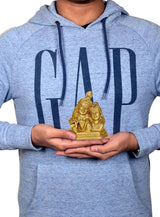 Radha Krishna murti held in hands, small gold-tone deity statue on palms