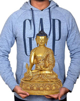 Gold Buddha statue idol held in front of light blue hoodie, blue jeweled crown visible