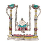 Front view of Lord Ganesha on brass swing jhula with colorful base, chains visible
