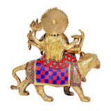 Brass Durga statue from behind on lion, blue-red patterned cloth and ornaments