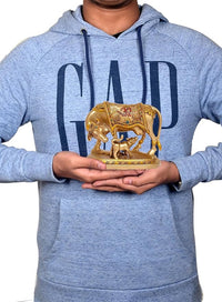 Resin cow with calf figurine held in hands, gold tone, pooja mandir decor