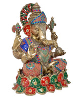 Ganesha brass idol with green, red, and blue details; trident and hands visible