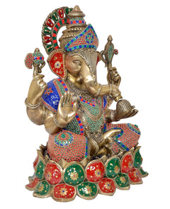 Ganesha brass idol with green, red, and blue details; trident and hands visible