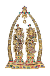 Brass Radha-Krishna statue with ornate arch, colorful details, hanging bell
