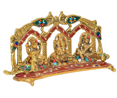 Close view of Ganesh, Laxmi, Saraswati metal idols under peacock arch frame