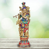 Brass Krishna murti with colorful attire and ornate gold detailing, holding flute