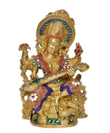 Brass Saraswati statue front view, seated goddess with flute, peacock and colorful gem details