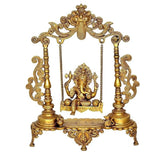 Gold brass Ganesha seated on swing with ornate frame and hanging chains