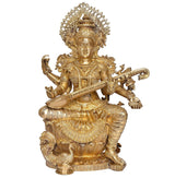 Brass Saraswati idol seated with veena across lap, detailed headdress and ornaments