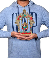 Brass Ganesha swing statue held in hands, ornate arch with turquoise and red details