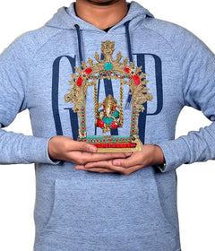 Brass Ganesha swing statue held in hands, ornate arch with turquoise and red details