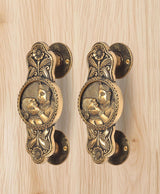 Brass door handle pair showing round rosettes and two-god & goddess oval relief design