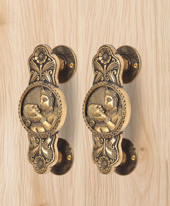 Brass door handle pair showing round rosettes and two-god & goddess oval relief design