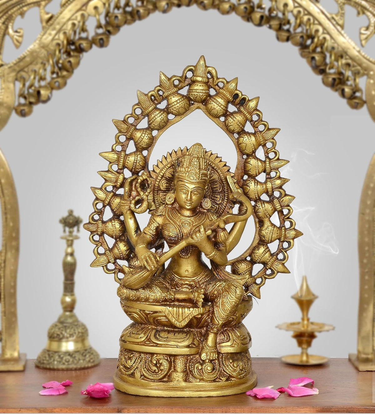 Brass Saraswati idol with ornate circular halo, seated goddess holding veena