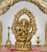 Brass Saraswati idol with ornate circular halo, seated goddess holding veena