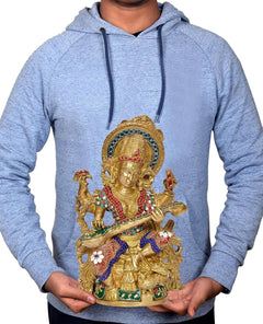 Hands holding brass Saraswati statue, seated goddess with flute and colorful jeweled dress