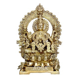 Brass Lakshmi idol with carved frame and Kirtimukha, seated on lotus