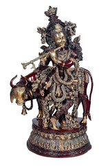 Brass Krishna with cow murti, raised flute, ornate metallic work, maroon accents