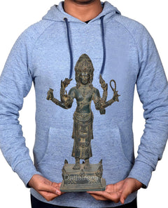 Four-armed Vishnu statue held by hands, ornate headdress and pedestal on display