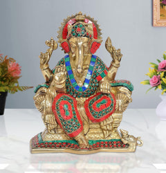 Brass Ganesha idol sitting with jeweled red, teal, and gold crown and four raised arms