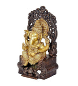 Side view Ganpati idol seated on dark carved singhasan, gold finish