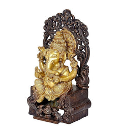 Side view Ganpati idol seated on dark carved singhasan, gold finish