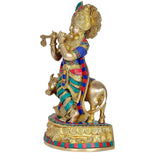 Side view brass Krishna with cow, colorful striped blue red outfit and flute