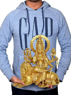 Brass Durga Maa statue on lion held in front of a blue hoodie