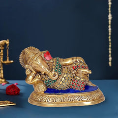 Brass Ganesha idol in resting pose, red and green jeweled details, blue base