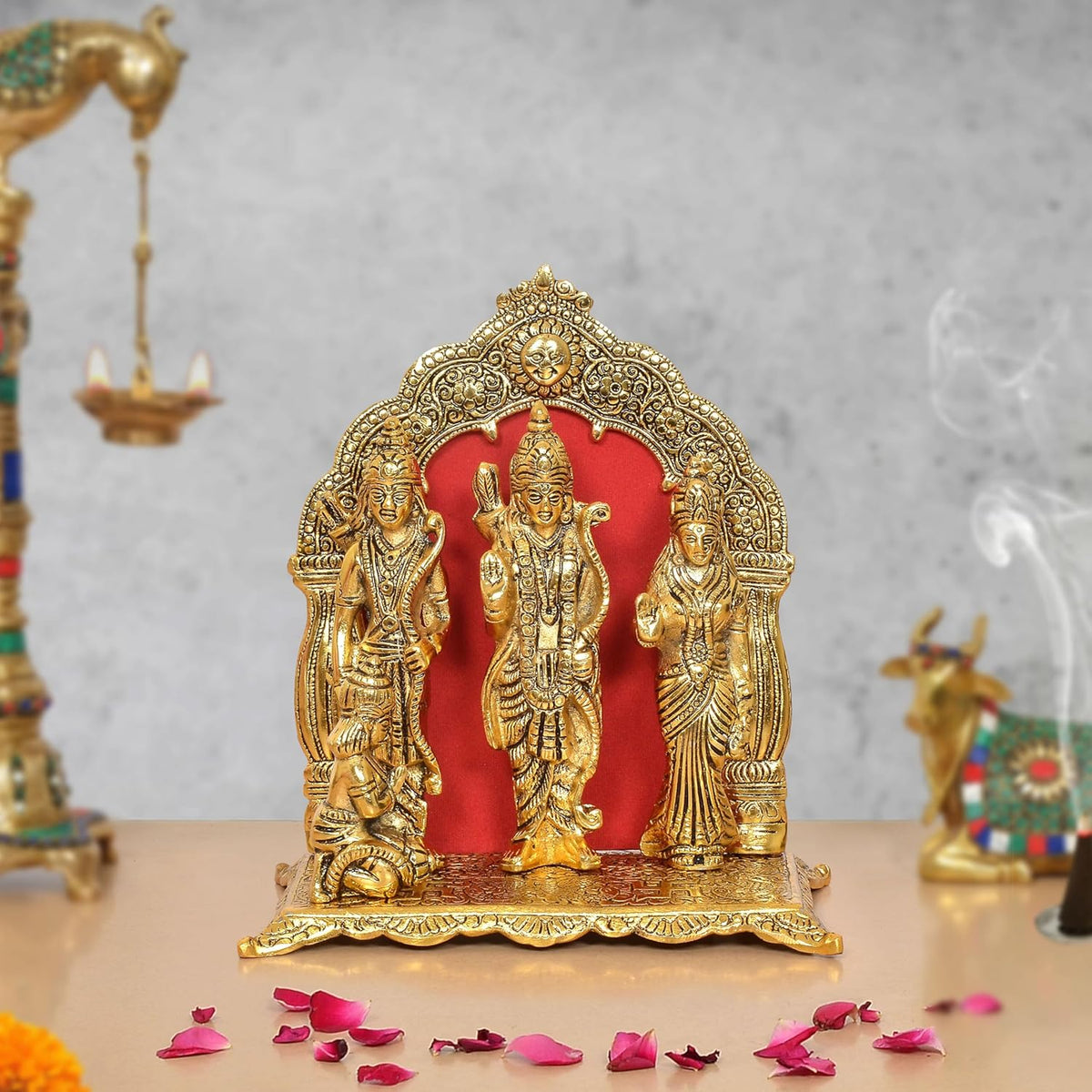 Metal Ram Darbar statue: three seated figures under golden arch with red backdrop