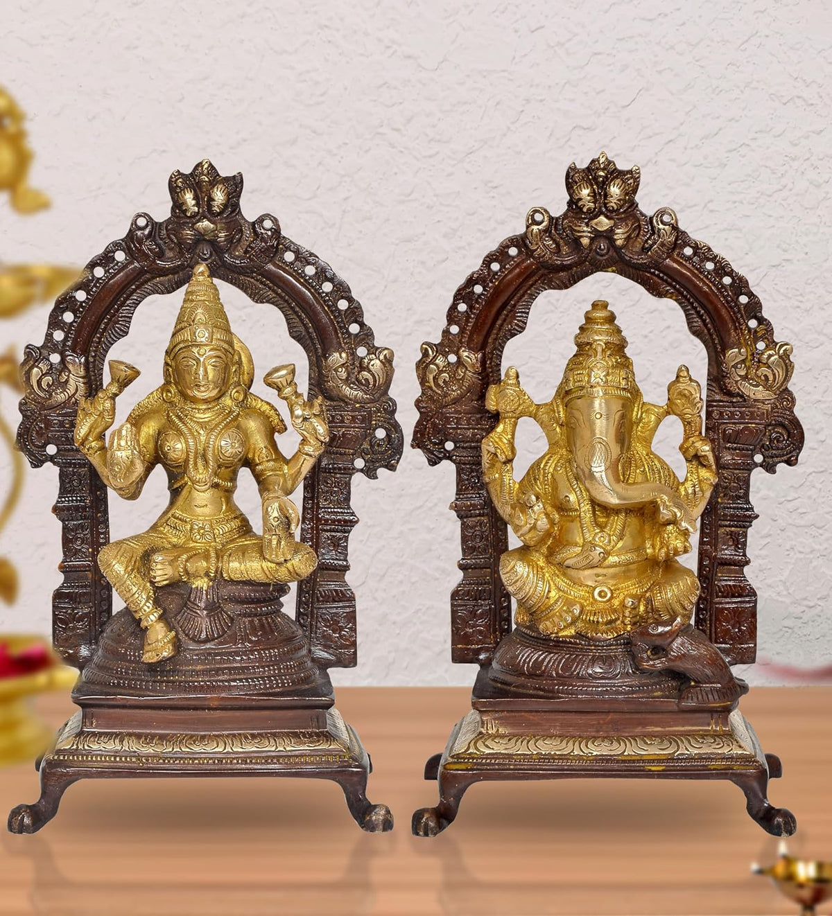 Brass Lakshmi and Ganesha idol pair with ornate arch, golden figures on dark base