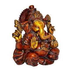 Angled view of Ganesha idol seated on lotus, gold face, red-brown carved detail