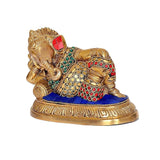 Brass Ganesha resting idol with jeweled necklace, red accents, and blue cushion