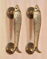 Matched pair of golden brass fish door handles with round rosettes and screws.