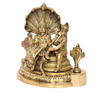 Close view of golden brass Maa Lakshmi with Lord Vishnu beside Sheshnag base