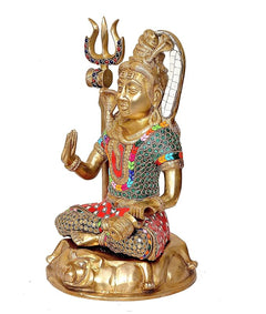Seated Lord Shiva brass idol side view, folded hands, trident with enamel details.