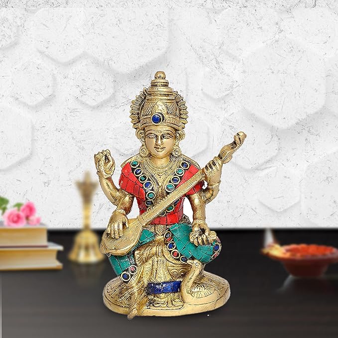 Brass Saraswati murti with red-and-teal sari, blue eye, raised hands, seated on base