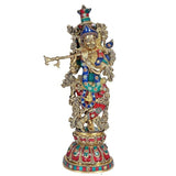 Krishna brass sculpture with teal, blue and red jeweled clothing, holding a long flute
