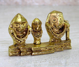 Close-up of golden trio idol figures with carved facial details and ornate base
