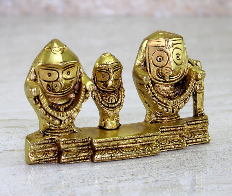 Close-up of golden trio idol figures with carved facial details and ornate base