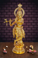 Gold brass Krishna murti playing flute with cross staff, on round base