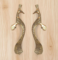 Gold peacock-shaped door handle pair with bird heads, curved bodies, and decorative grips