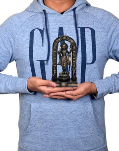Ram Lalla brass statue held in hands on grey hoodie, arched design visible