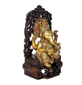 Ganpati statue in profile on ornate singhasan, gold figure with dark base