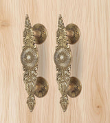 Golden brass door handle pair, side view of scrollwork and curved rosette discs