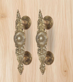 Golden brass door handle pair, side view of scrollwork and curved rosette discs